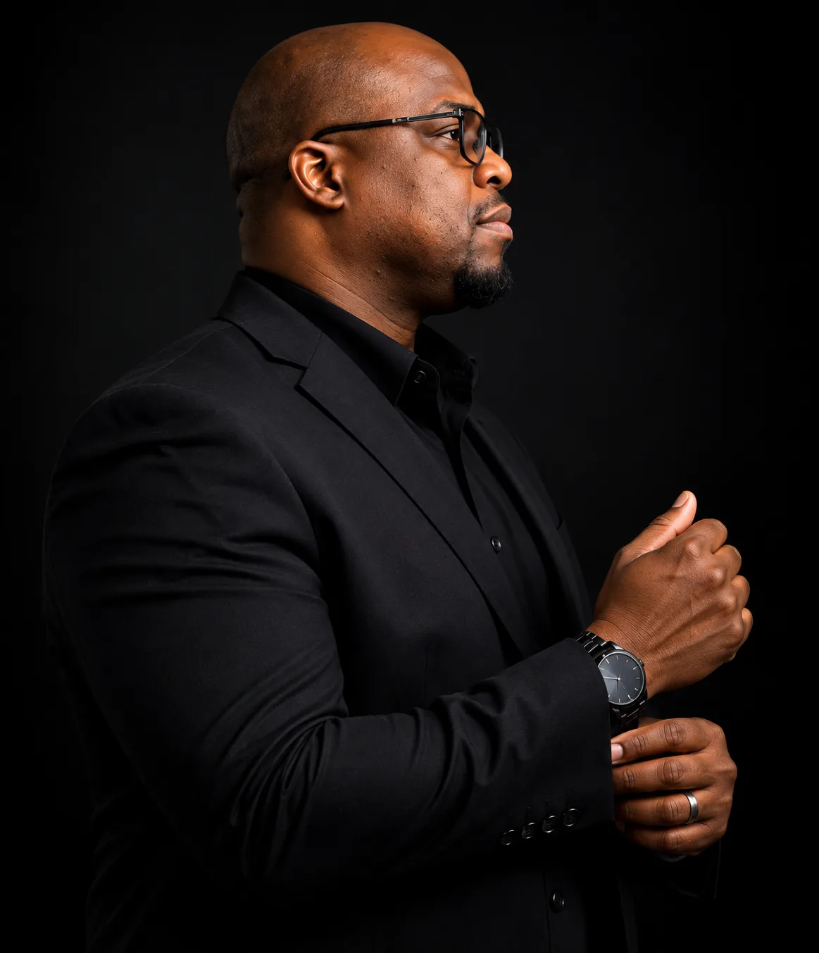 Profile portrait of Stephan Tiller in a black suit against a dark background